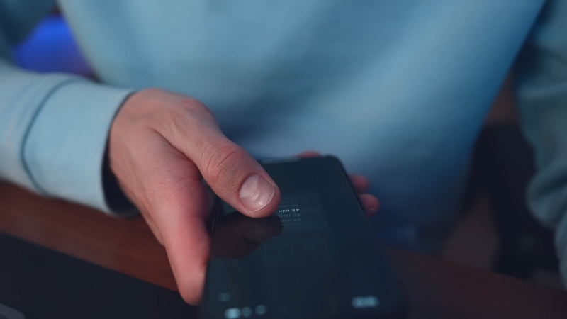 A Person in A Light Blue Sweater Using a Smartphone with A Timer App Open